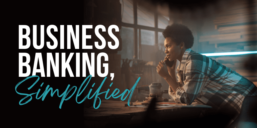 A young African American woman on the phone in a workshop. At the left, the words: Business Banking, Simplified.