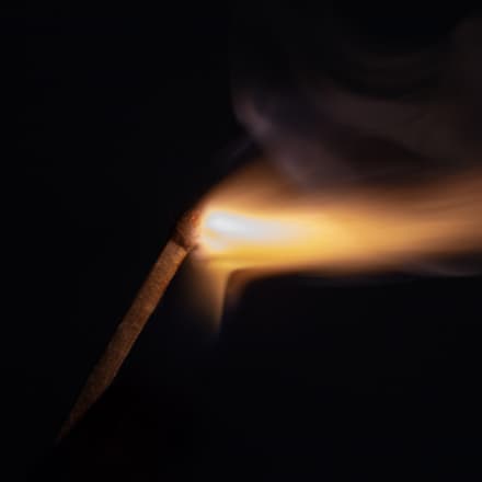 A burning match against a dark background.