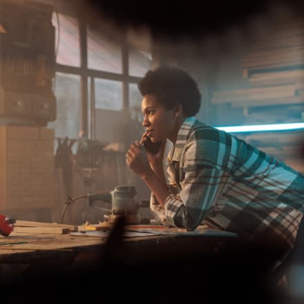 A young African American woman on the phone in a workshop.