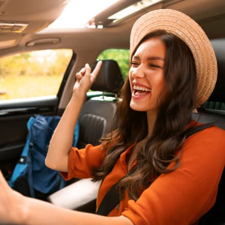 A happy young woman singing inside her car.
