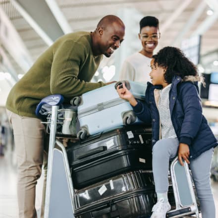 A smiling African American family with luggage at the airport.