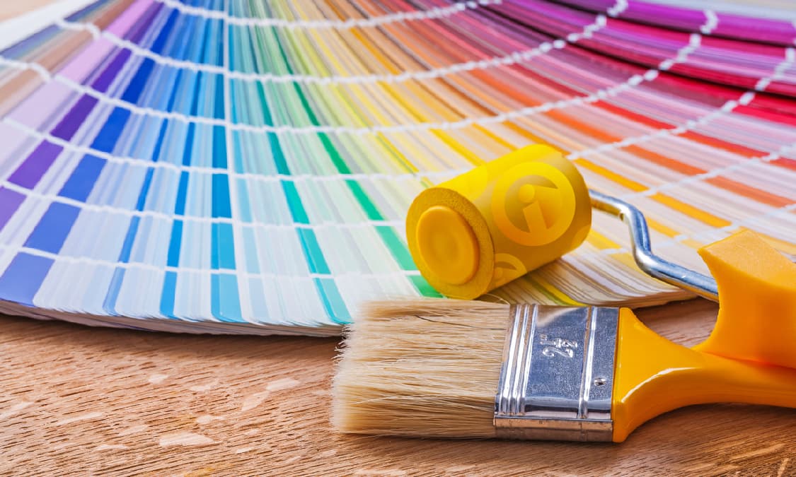 A colorwheel and a paint brush laying on a wooden surface.