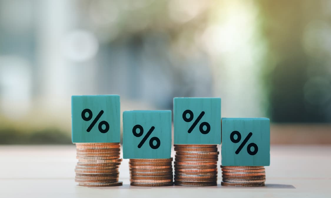 Four stacks of coins, each topped with a cube displaying a percent symbol on its face.