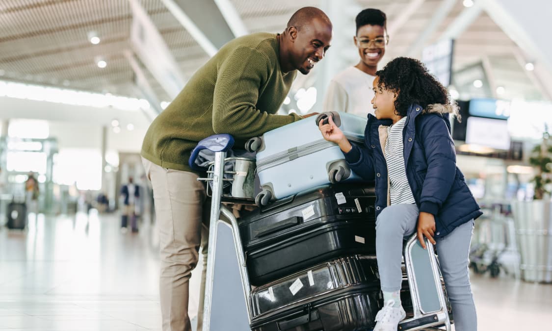 A smiling African American family with luggage at the airport.