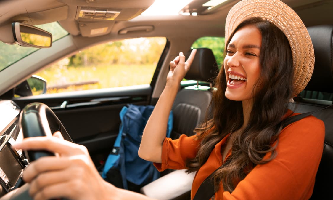 A happy young woman singing inside her car.