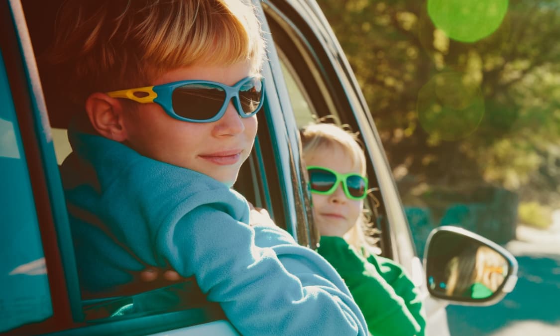Two young children looking out the windows of a car.